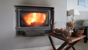 Un poêle à bois avec un bol en verre rempli de noix, posé sur une table en bois.