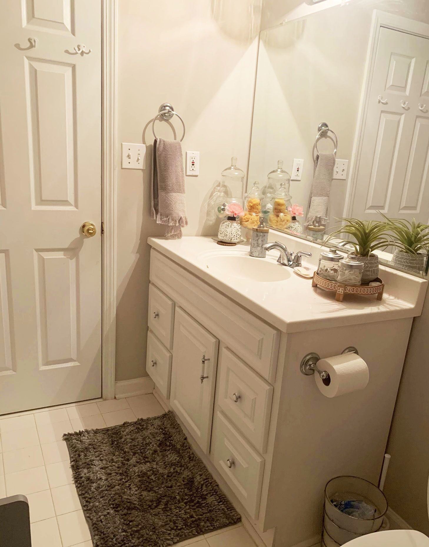 Une salle de bain avec un meuble-lavabo blanc, un miroir, un porte-serviettes et un porte-rouleau de papier toilette.