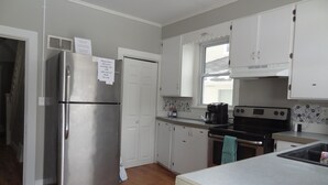 Cocina compacta con gabinetes blancos, un refrigerador de acero inoxidable, una estufa y una cafetera.
