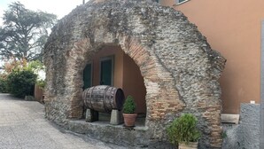 An old stone archway with a barrel and potted plants. - Villa Capri Bernabei, Domus Romana with private swimmingpool (Ciampino)