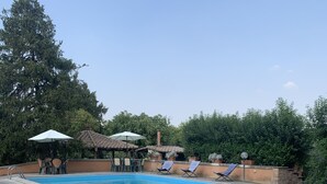A swimming pool with lounge chairs and umbrellas, surrounded by stone flooring and greenery. - Villa Capri Bernabei, Domus Romana with private swimmingpool (Ciampino)