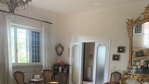 A spacious living room with a chandelier, floral-patterned sofas, a coffee table, and a large mirror. - Villa Capri Bernabei, Domus Romana with private swimmingpool (Ciampino)