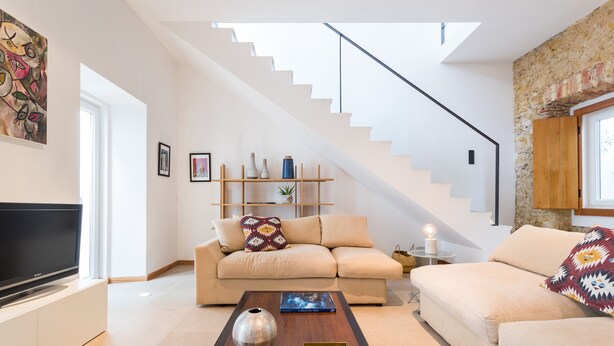 A modern living room with a sofa, coffee table, and a staircase.