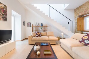 A modern living room with a sofa, coffee table, and a staircase.