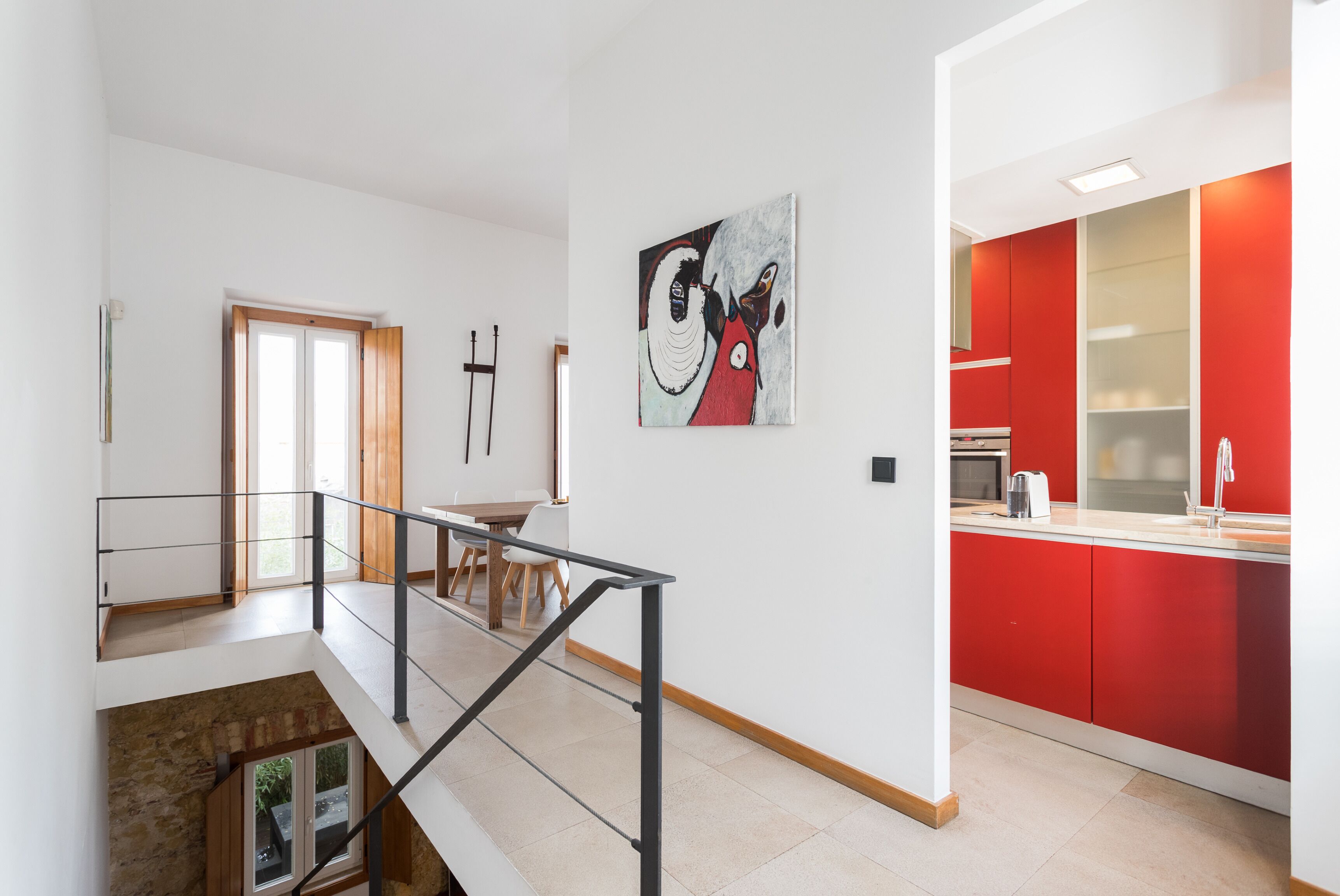 Une cuisine moderne avec des meubles rouges et un coin repas comprenant une table et des chaises en bois.