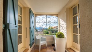 Un balcon avec une chaise blanche, un pot de fleurs et une vue sur les montagnes.