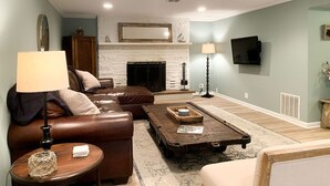 A living room with a fireplace, leather sofa, coffee table, and lamps. - Beach nearby-pure summer/winter magic awaits! (Genoa City)