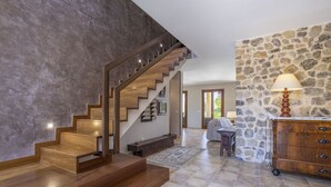 Ein modernes Interieur mit einer Holztreppe, einer Steinwand und einer Lampe auf einem Holzkabinett.