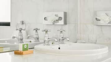 A bathroom with three faucets, a large sink, and a soap dispenser on a wooden tray.