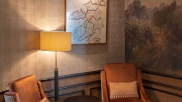 A room with two leather armchairs, a floor lamp, a round table, and a map on the wall.