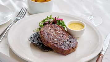 Un piatto con una bistecca, patatine fritte, insalata e una piccola ciotola di salsa.