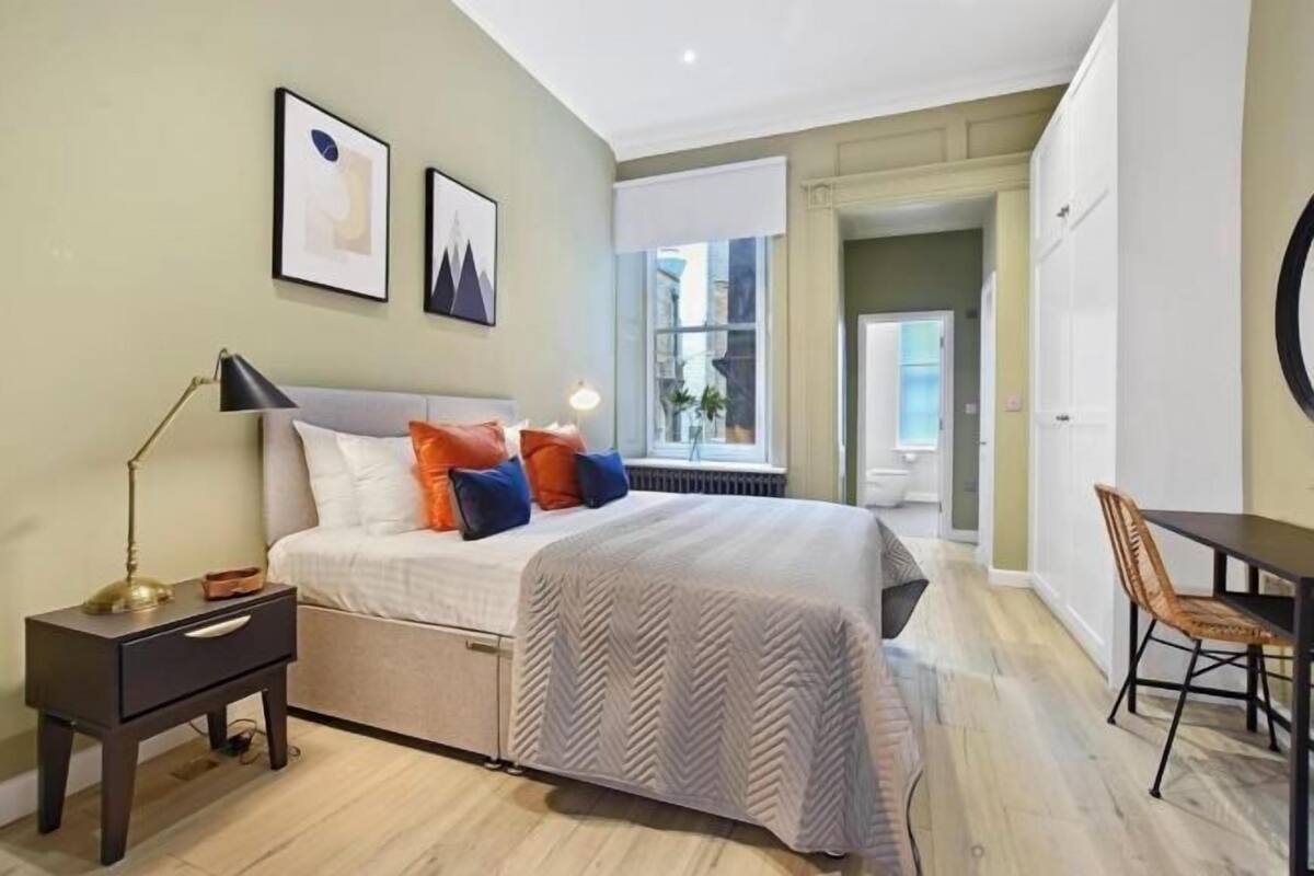 A bedroom with a bed, bedside table, lamp, and a view of a balcony.