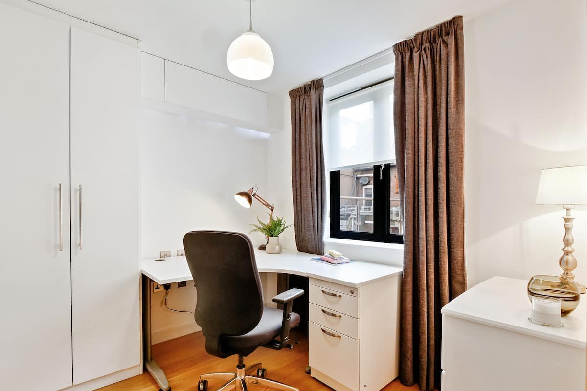 A modern office space with a desk, chair, and a window with curtains.
