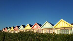 A row of colorful beach huts with numbered doors, set against a clear blue sky. - Penn House Hotel (Weymouth)