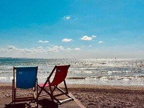 Una playa con dos sillas y una terraza de madera.
