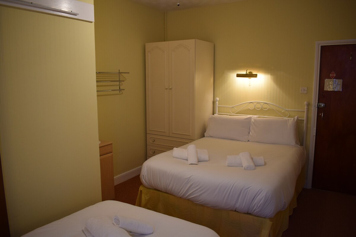 A hotel room with two beds, a wardrobe, and a door.