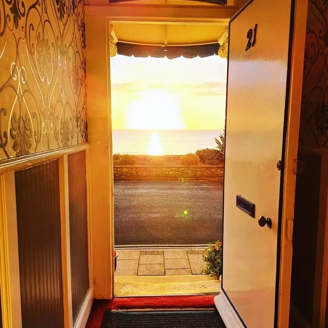 A doorway leading to a street with a sunset view.