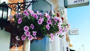 A hanging flower basket with pink flowers in front of a building with a sign that reads "Penn House Hotel". - Penn House Hotel (Weymouth)