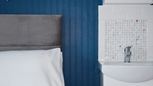 A bathroom with a white sink, blue walls, and a wooden headboard. - Penn House Hotel (Weymouth)