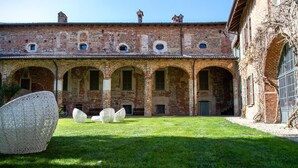 A courtyard with a brick building featuring arched windows and a covered walkway.