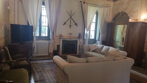A living room with a fireplace, a sofa, a television, and a patterned rug.