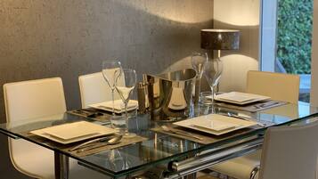 Een moderne eetruimte met een glazen tafel, witte stoelen en een metalen decoratiestuk.