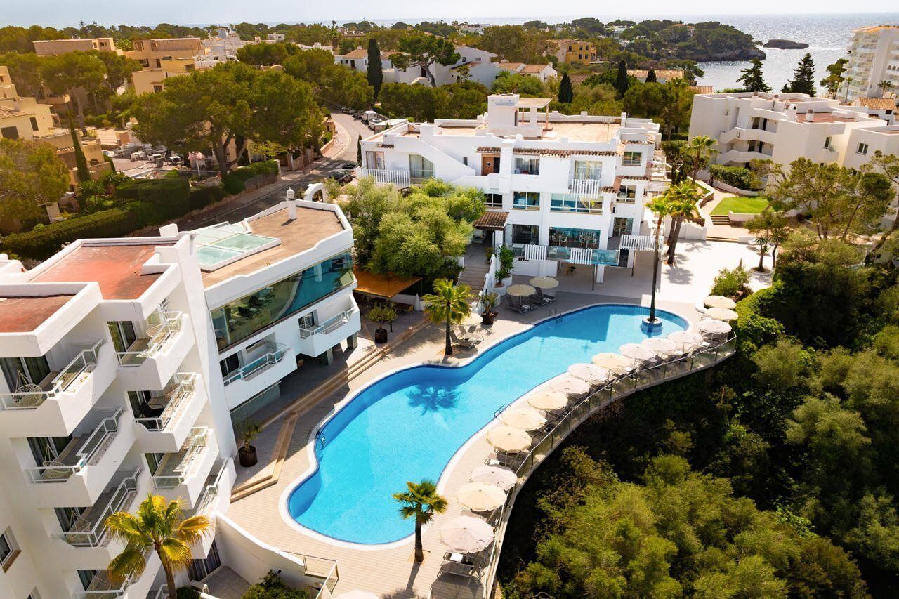 A modern hotel with a swimming pool, balconies, and a view of the sea.