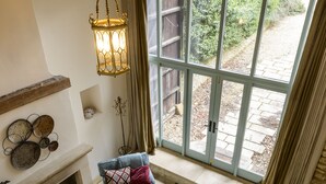 A staircase leading to a landing with a view of a garden through large windows. - The Hall - luxury barn conversion in the Cotwolds (Bristol)