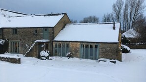 A stone house with a snow-covered roof and a small porch. - The Hall - luxury barn conversion in the Cotwolds (Bristol)