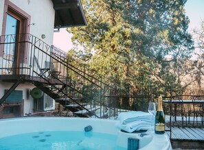 A hot tub with a bottle of champagne and towels, a staircase leading to a balcony, and a view of trees. - Le Grand Petit Prince I Charming House 6 pers I Private Jacuzzi (Guebwiller)
