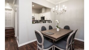 A dining area with a wooden table, six chairs, a chandelier, and a kitchen visible through an archway. - "Contemporary townhouse-style condo in West Hollywood." (Los Angeles)
