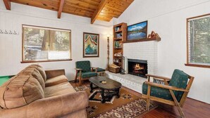 Un salon chaleureux avec une cheminée, un plafond en bois et de grandes fenêtres.
