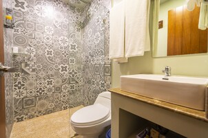 Un baño con baldosas estampadas, un inodoro blanco, un lavabo y un espejo.