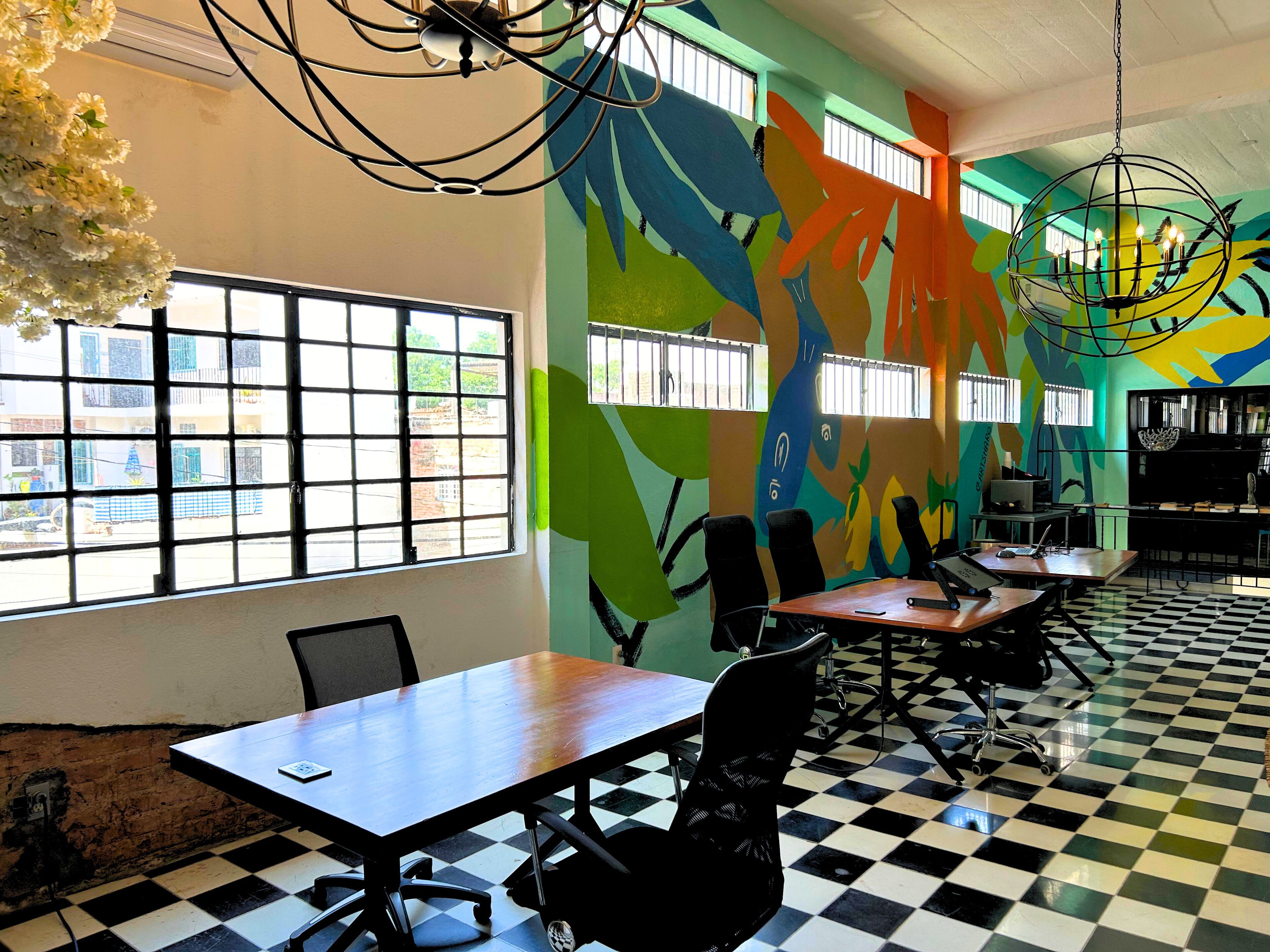 Une salle de conférence dotée d’un sol à carreaux, de grandes fenêtres et d’œuvres d’art murales abstraites et colorées.