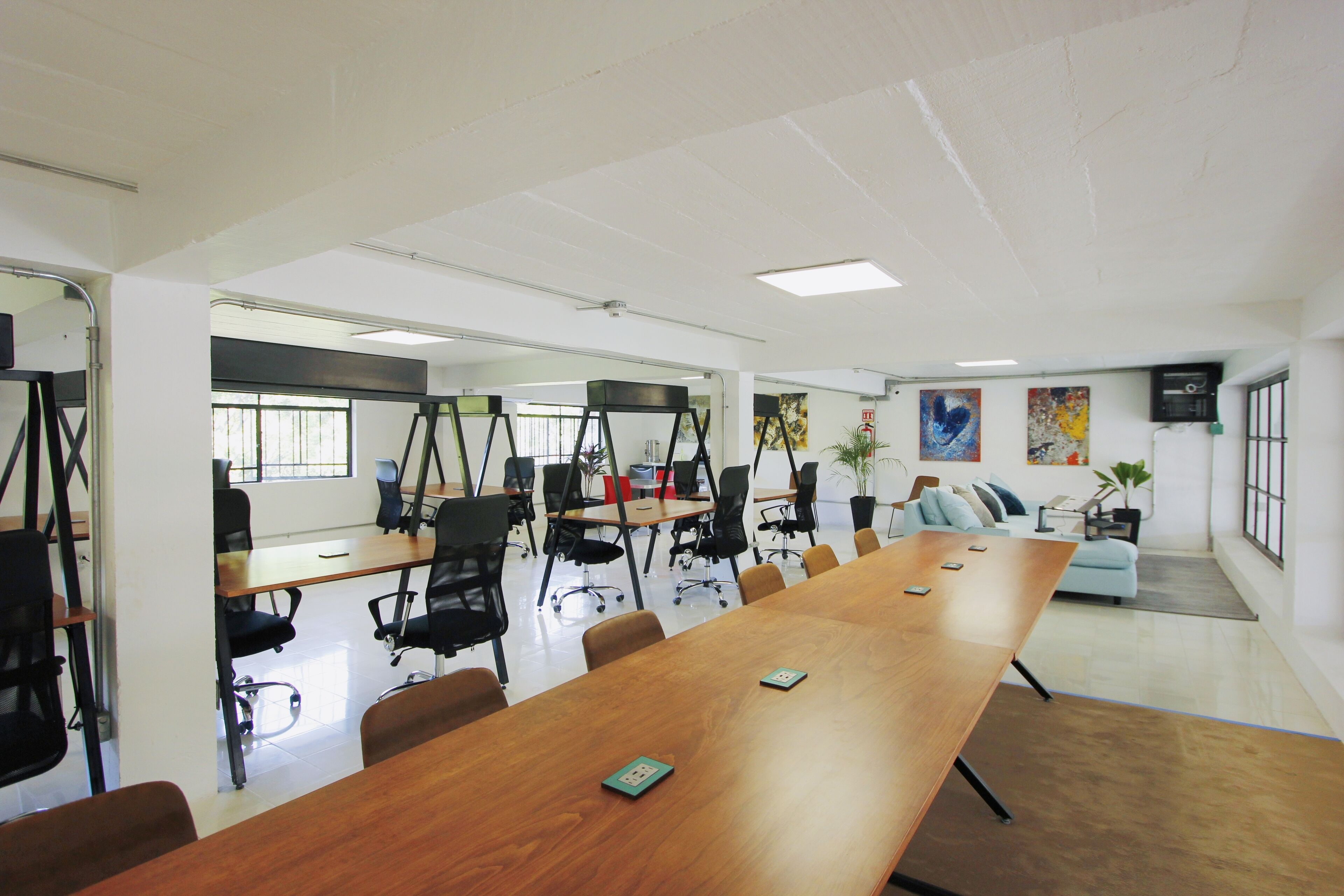 A conference room with a long wooden table, black office chairs, and a sofa in the background.