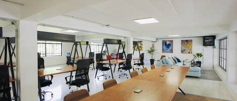 A conference room with a long wooden table, black office chairs, and a sofa in the background.