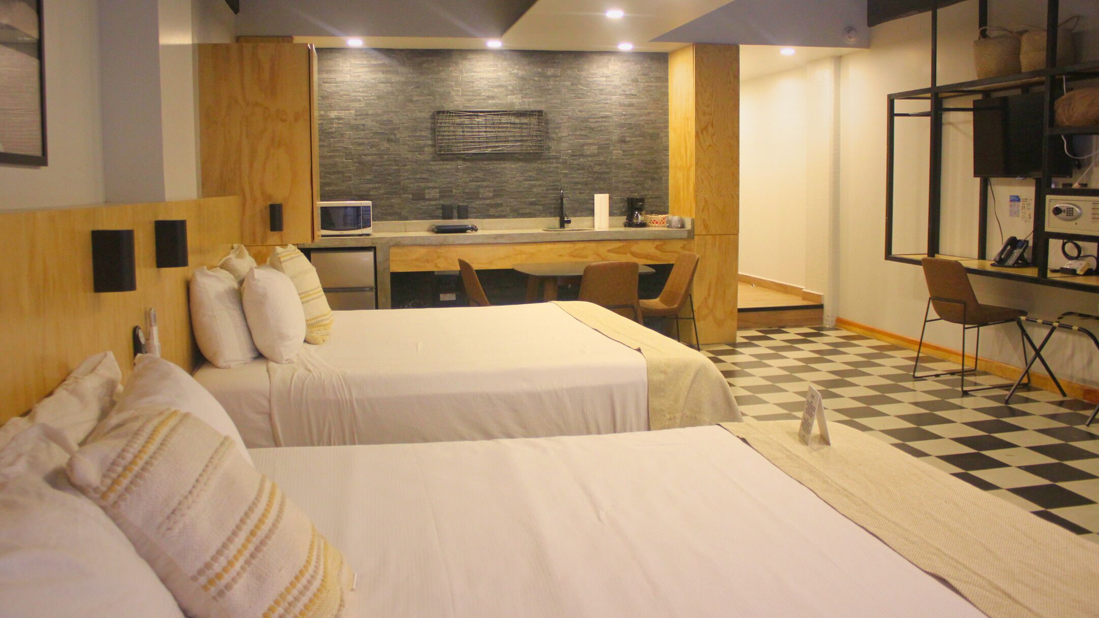 Habitación de hotel con dos camas, un escritorio, una silla, un microondas y un mostrador de recepción.