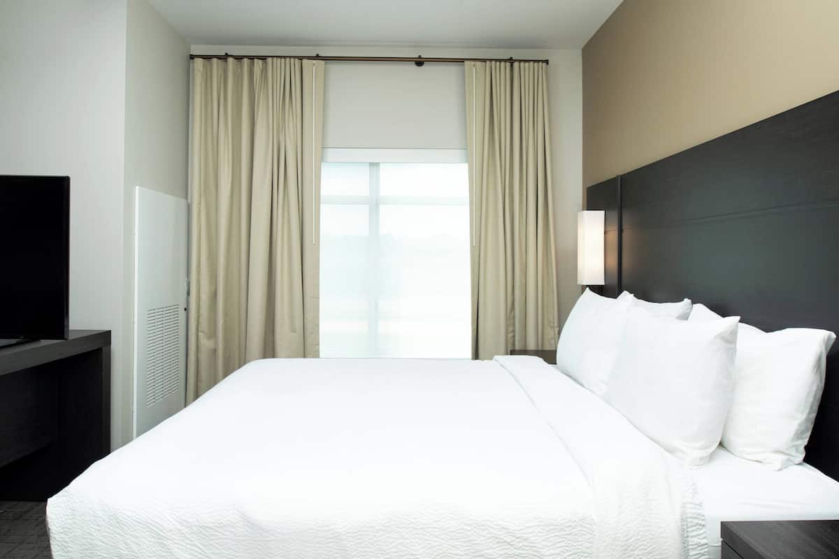 Une chambre d’hôtel avec un grand lit, un téléviseur à écran plat et une fenêtre avec des rideaux.