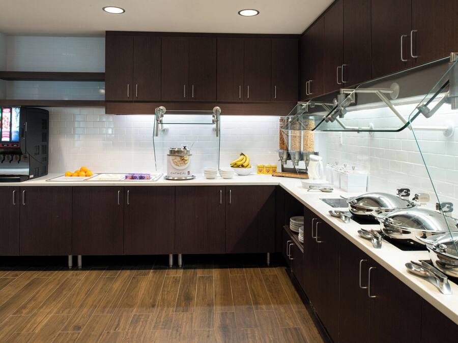 A modern kitchen with dark wooden cabinets, a white countertop, and a coffee machine.