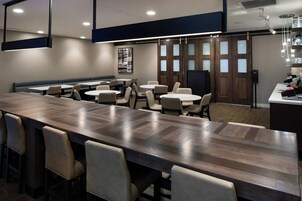 Un salón de conferencias con una larga mesa, varias sillas y una pequeña zona de kitchenette.