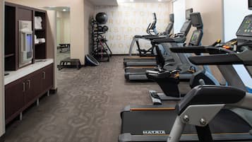 A fitness room with treadmills, a weight bench, and a wall with motivational text.