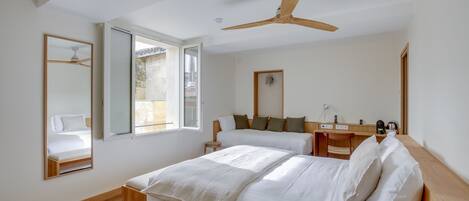 Un dormitorio moderno con una cama grande, un ventilador de techo, un escritorio y una ventana.