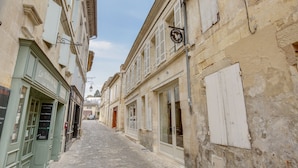 A narrow cobblestone street flanked by historic buildings with shuttered windows and a sign for 'Les Delices du Roy'. - Badon Boutique Hôtel (Saint-Émilion)