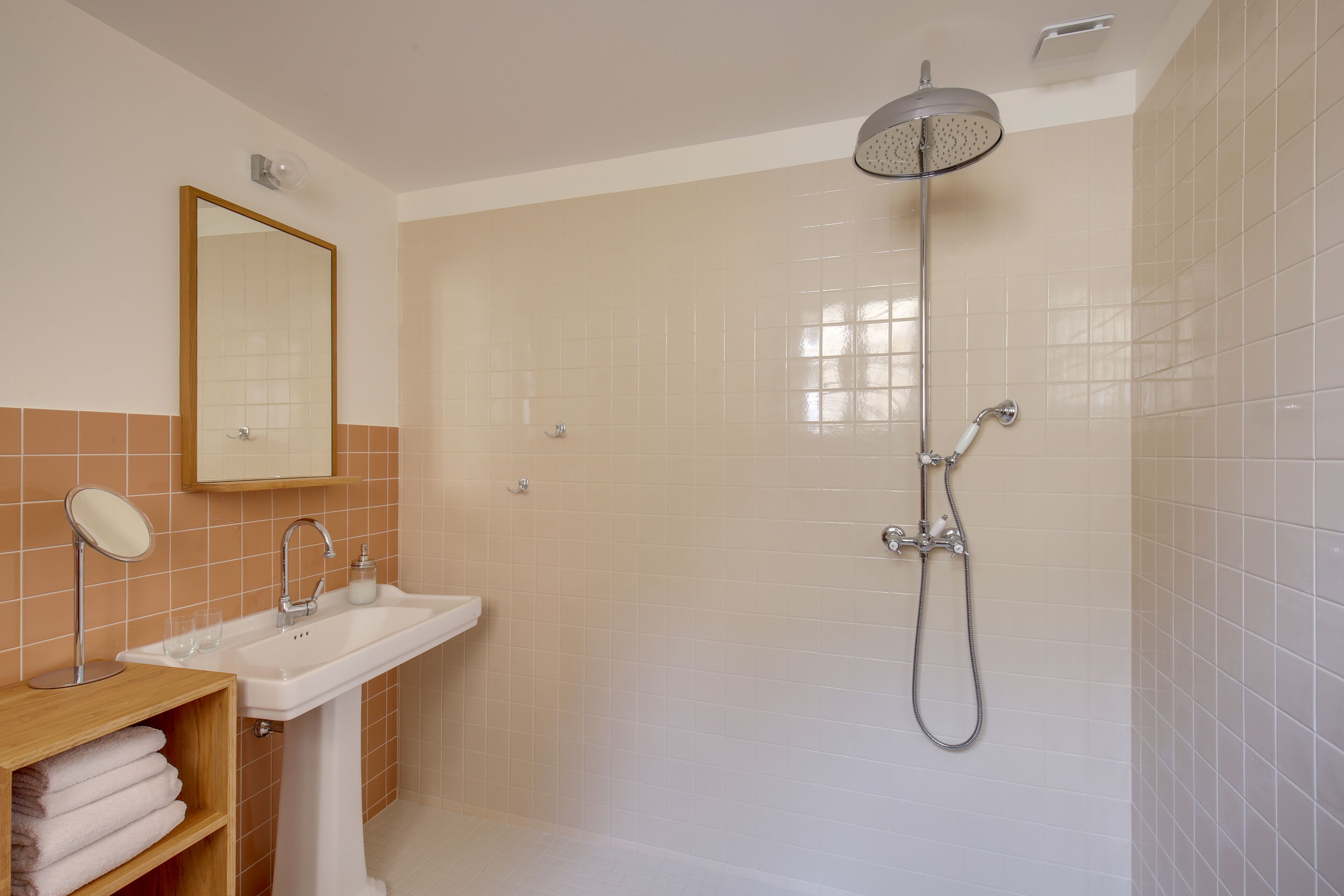 A bathroom with a sink, mirror, and shower.