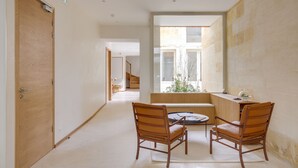 A modern interior with a wooden door, a staircase, and a seating area with two chairs. - Badon Boutique Hôtel (Saint-Émilion)