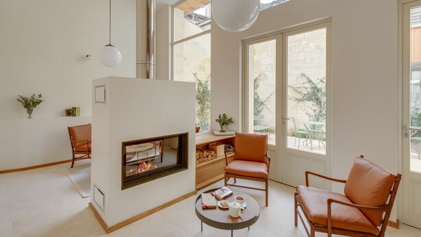 A spacious living room with a fireplace, large windows, and a view of the outdoors. - Badon Boutique Hôtel (Saint-Émilion)