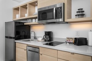 Una cocina moderna con electrodomésticos de acero inoxidable, microondas integrado y cafetera.