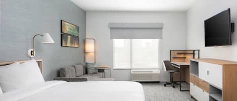 A hotel room with a large bed, a desk, a chair, a television, and a window with a view.