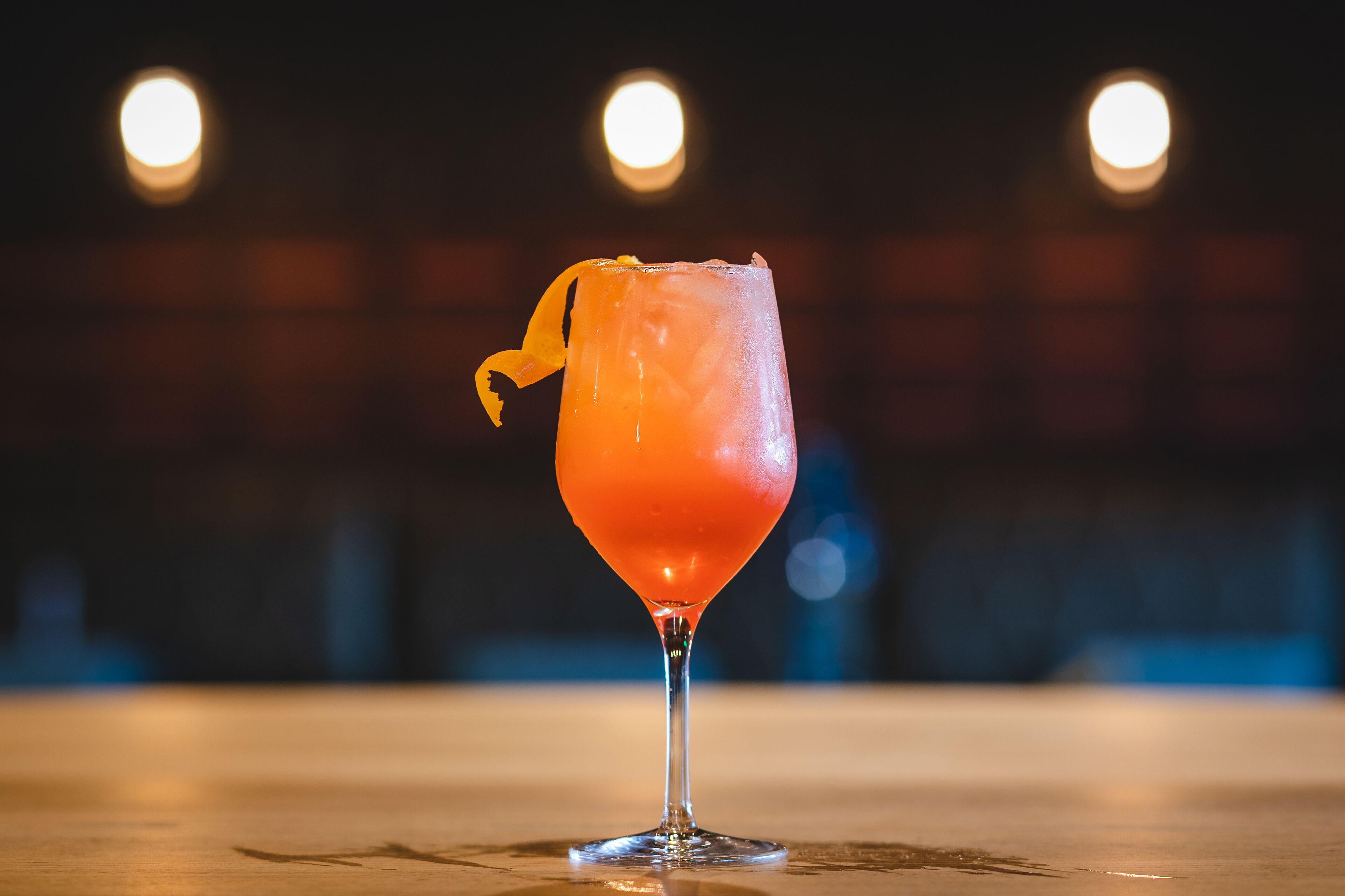 A cocktail glass with a lemon twist on a bar counter.
