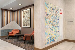 Um saguão de hotel com área de estar, um mapa abstrato grande e uma placa de boas-vindas.